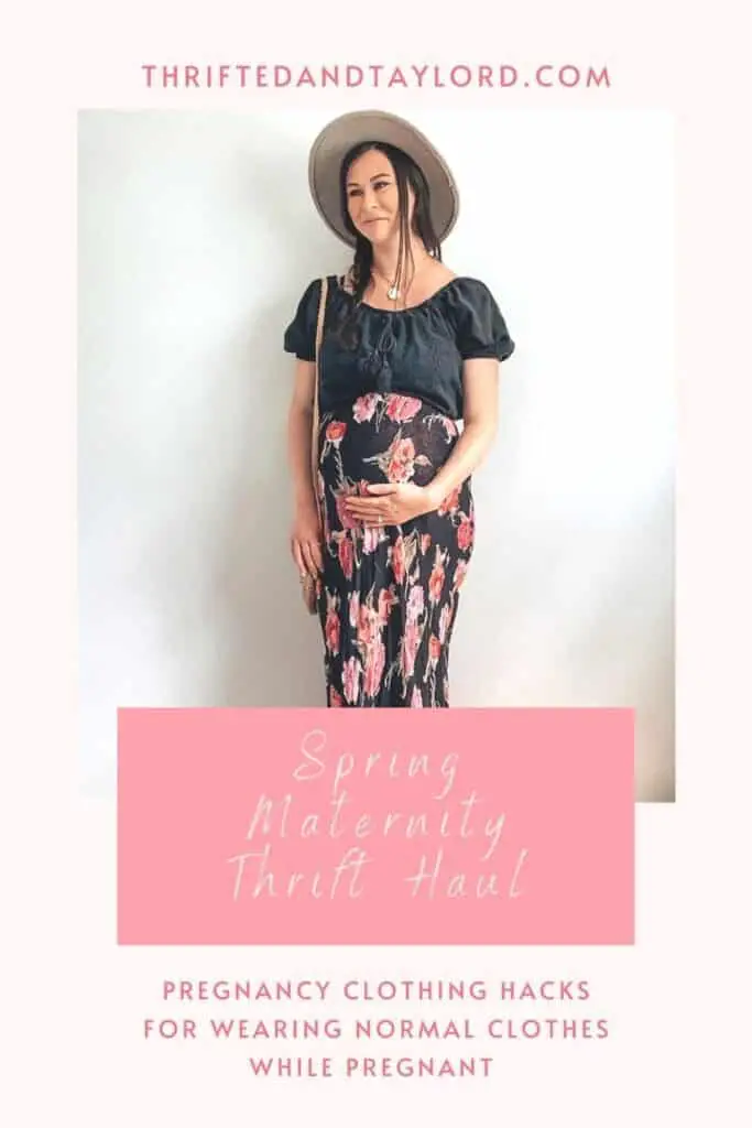 A pregnant woman wearing a black eyelet cropped shirt, a black maxi skirt with pink and purple flowers on it, a gray wide brim hat, a straw bag, gold necklaces, and taupe ankle boots. These are both maternity second hand clothes that are actually regular clothes you can wear while pregnant.