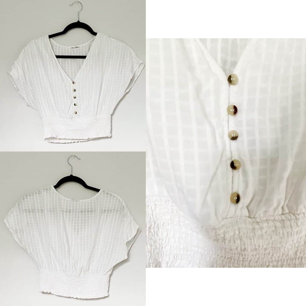 A white cropped shirt with buttons down the front and the waist is gathered.