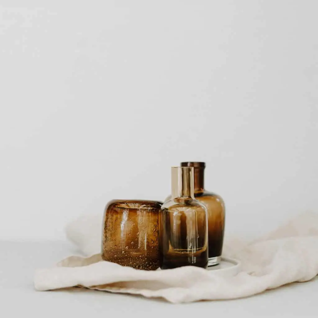 3 amber glass bottles on a cream cloth in an all white space.