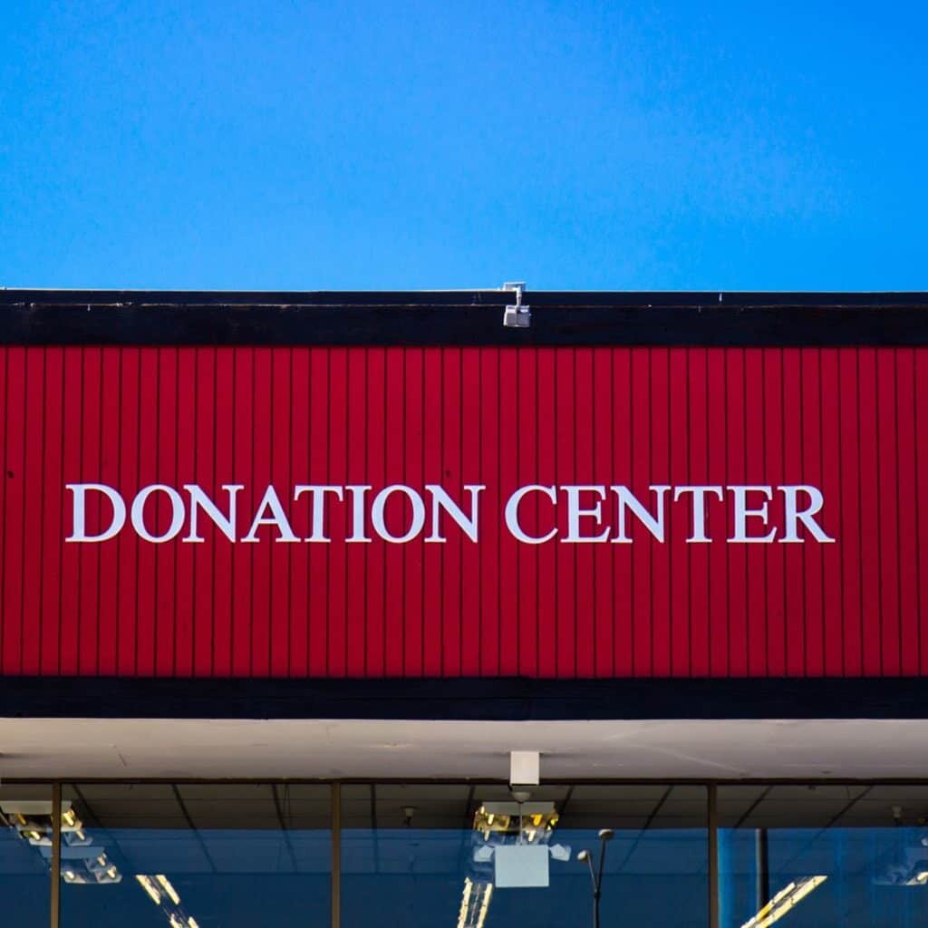 Recycling old clothes by donating them to a thrift store. A red building with "donation center" on it.