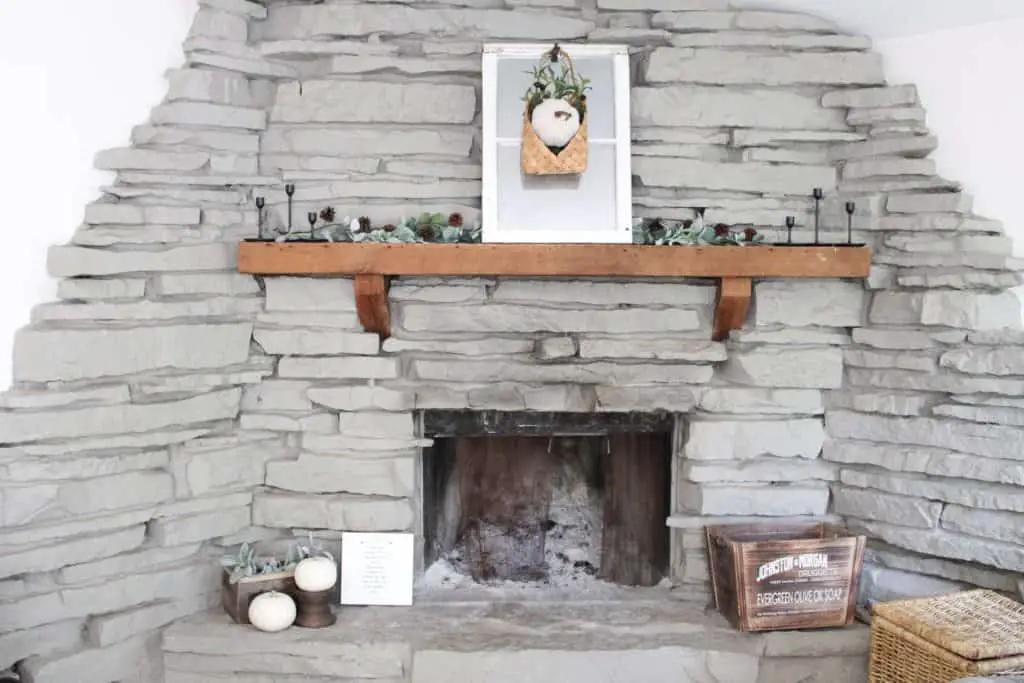 Decorating the fireplace using neutral fall decor mixed with the warmth of wood decor and pops of color from the greenery.