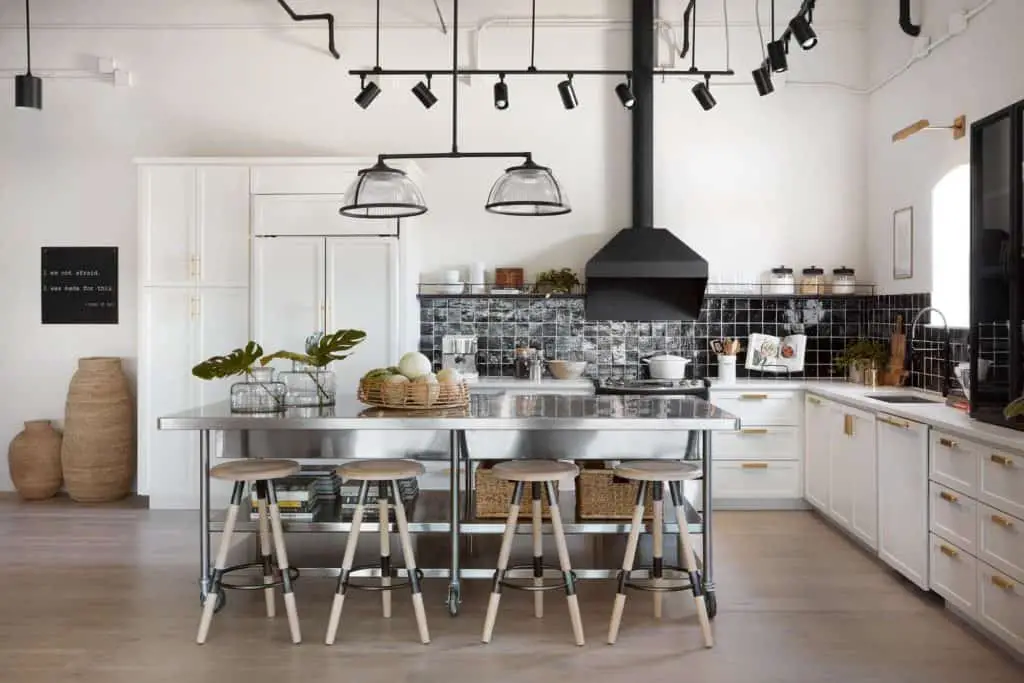 This Fixer Upper Kitchen is a mix of modern and industiral. It has a share black and white color scheme with metal and wood accents.