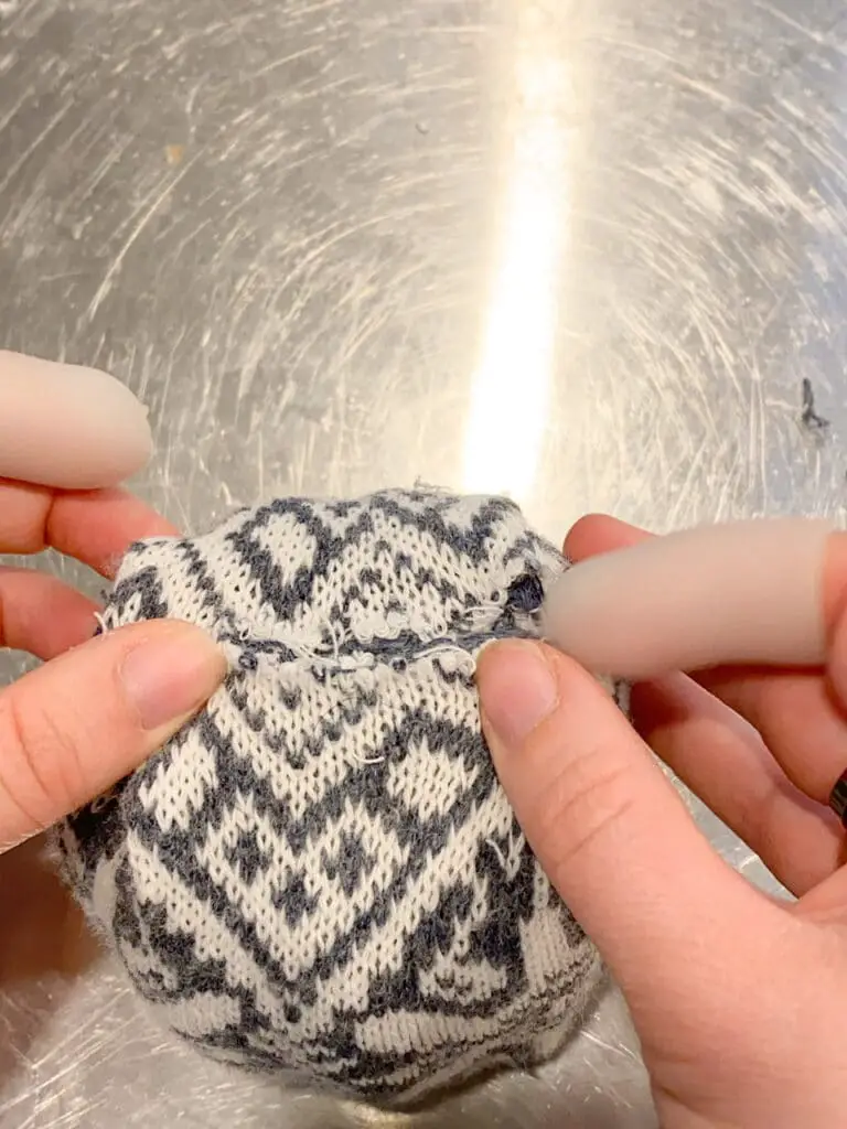 Photo show the bottom of one of the blue and cream DIY sweater pumpkins to demonstrate how to achieve the flattest bottom possible.