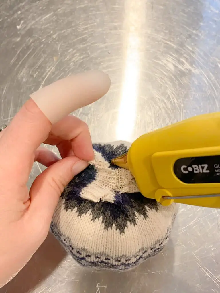 Photo shows adding some hot glue to the edges of the sweater fabric that needed to be glued down flat.