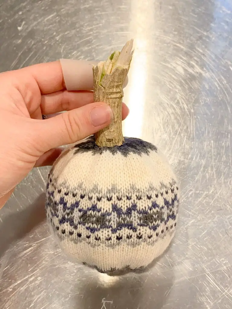 Photo shows one of the cream and blue patterned DIY sweater pumpkins after it was complete.