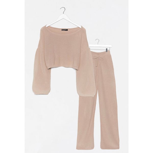 A tan knit lounge set, the top is cropped with long sleeves and the bottom is wide leg with a drawstring.