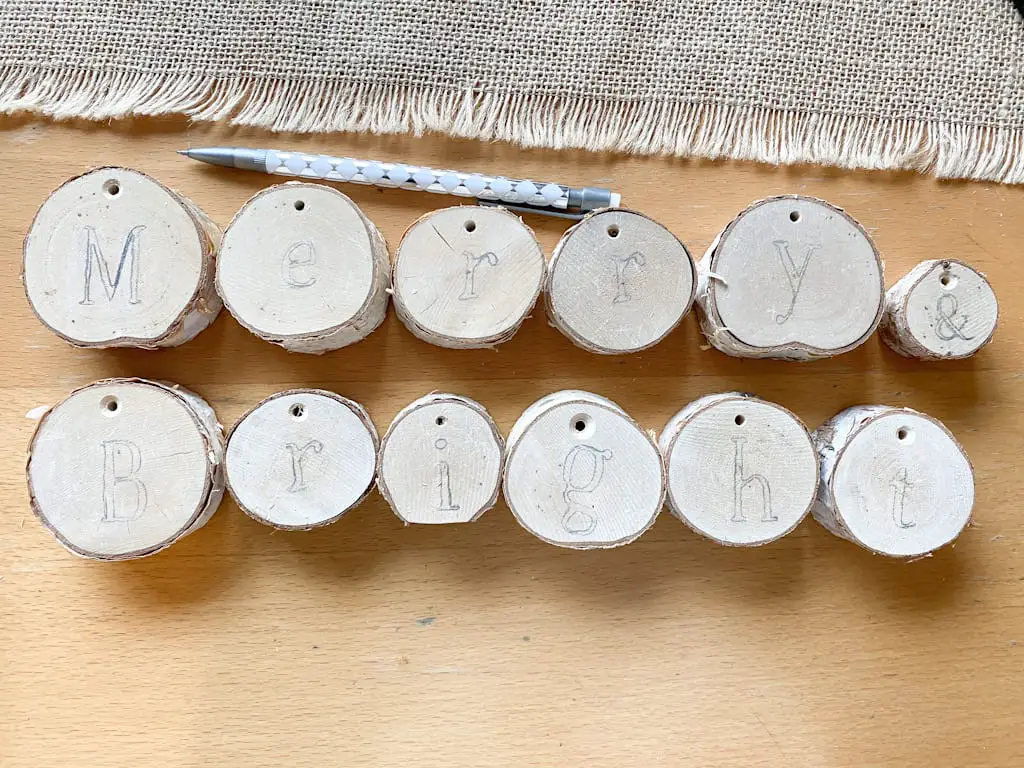 The words Merry & Bright written in pencil on slices of birch logs.