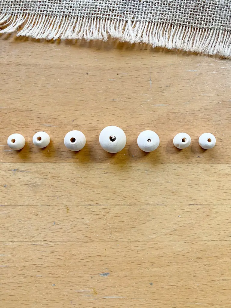 3 different sized wood beads arranged in a pattern for a wood bead garland.