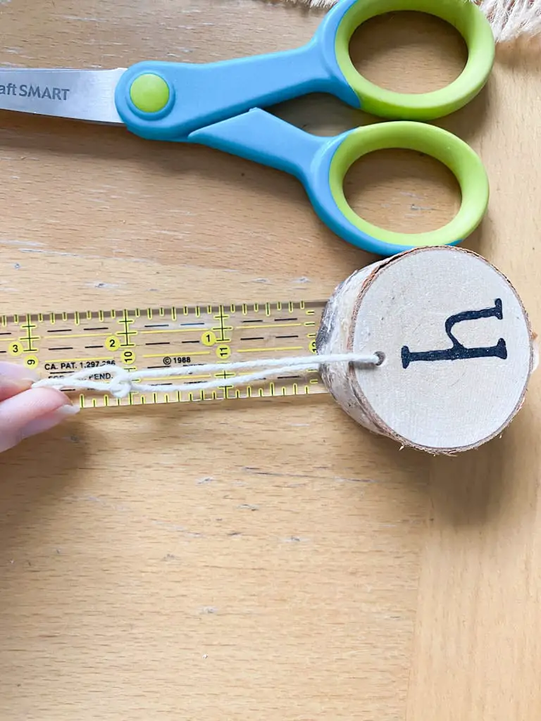 Measure cream string to 2 inches from the top of the wood to tie the knot.