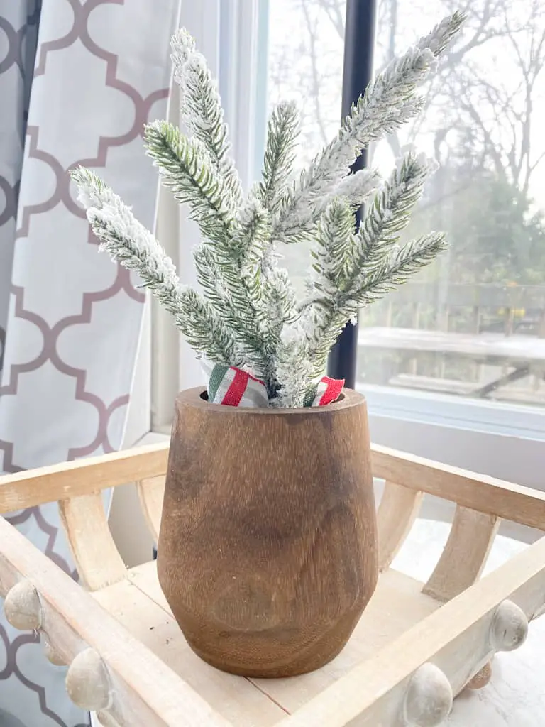 A flocked mini pine tree set inside a wood vase.