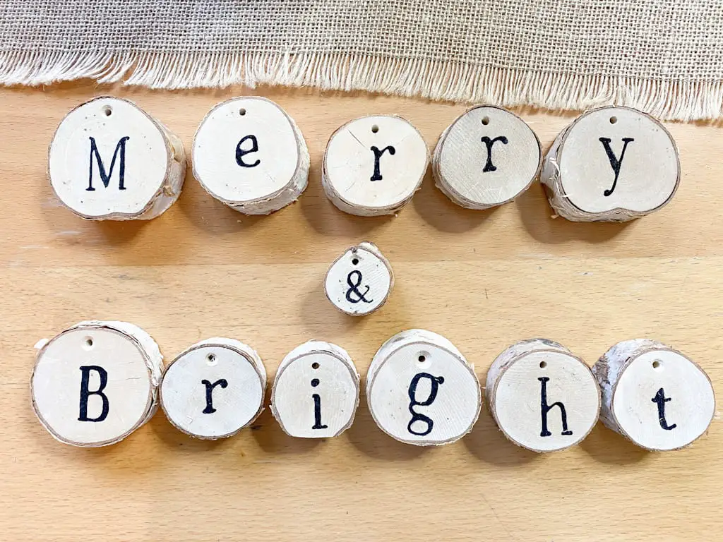 The words Merry & Bright written in black on slices of birch logs.