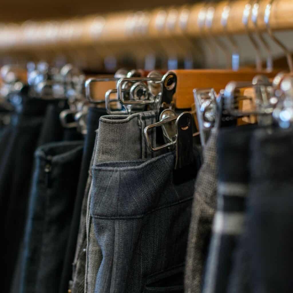 Assorted pants hanging on a rack.