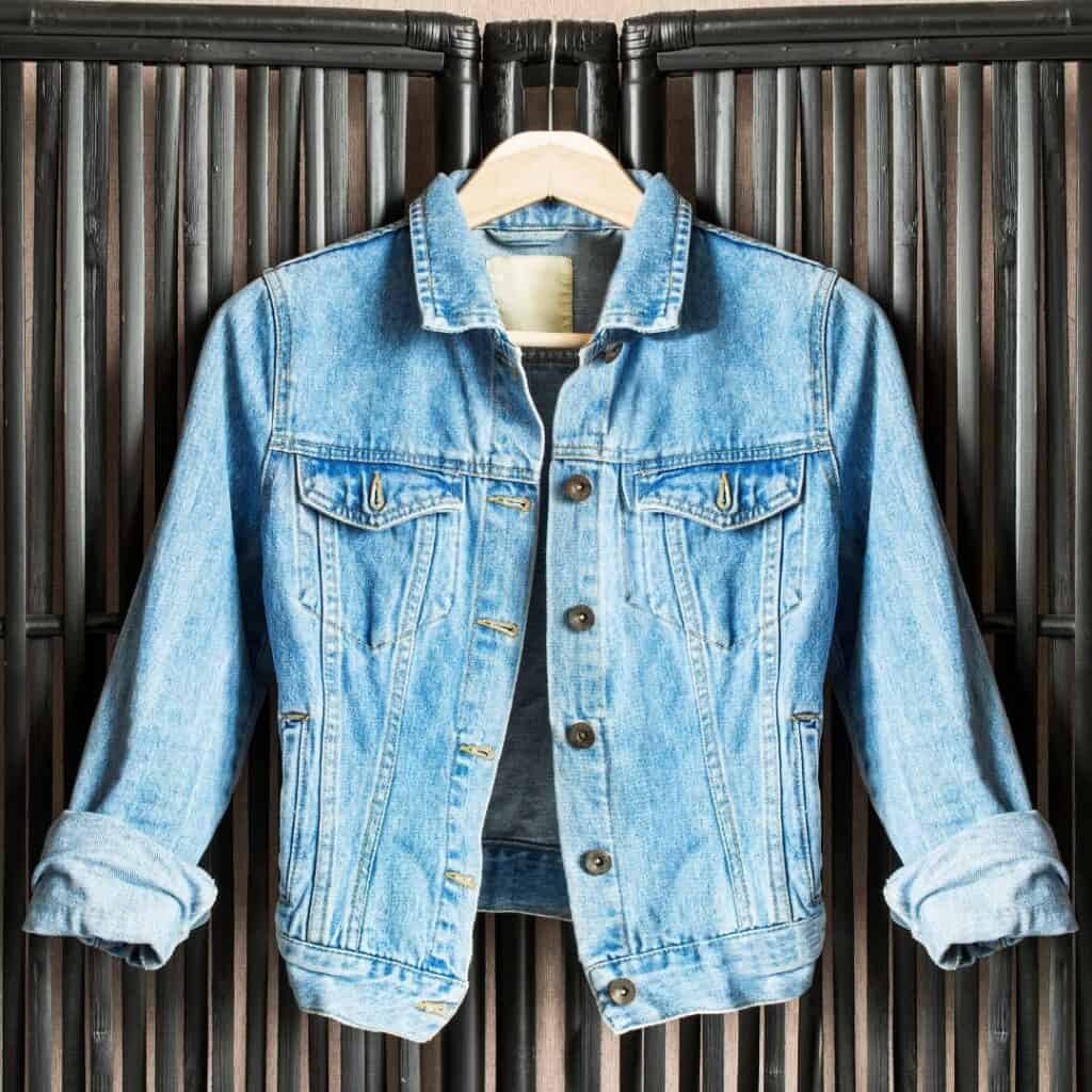 A denim jacket hanging on a black bamboo partition.