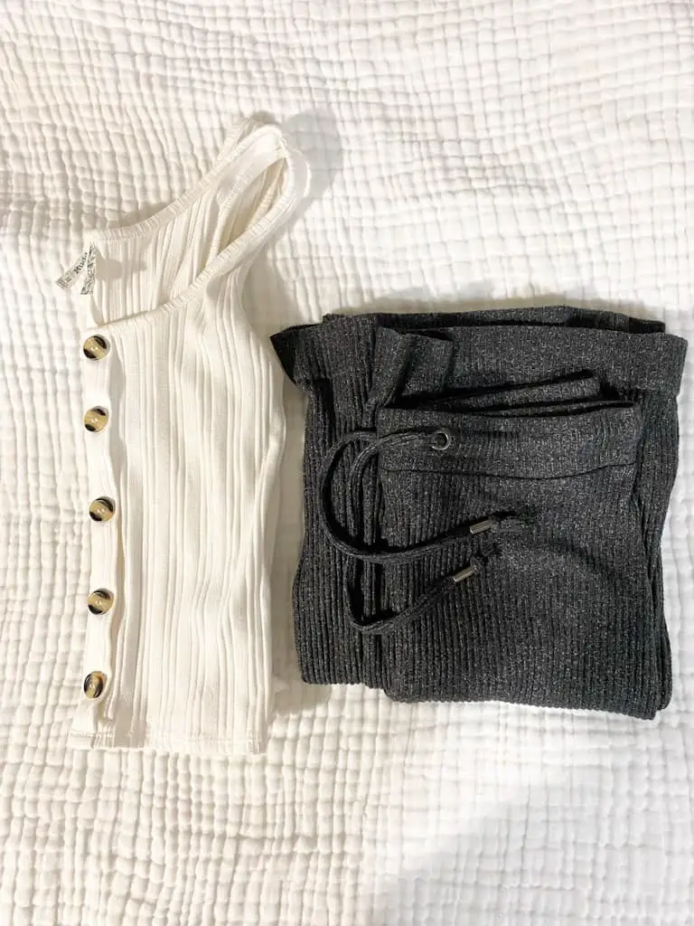 This is what's in my hospital bag for mom. A white tank top with buttons down the front and some gray high rise comfortable pants folded next to each other. to wear home