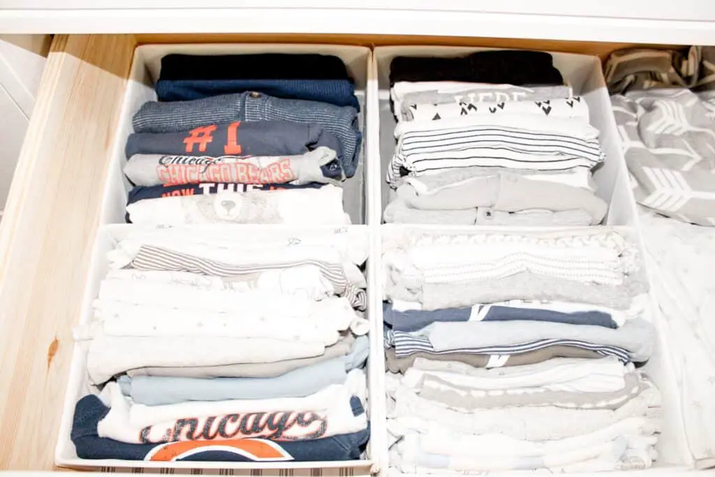 A dresser drawer with drawer organizers that house baby bodysuits.