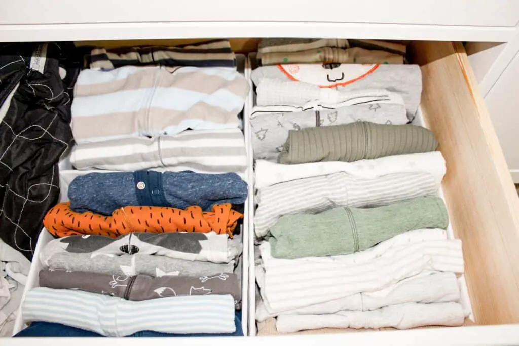 A dresser drawer with drawer organizers that house baby pajamas.