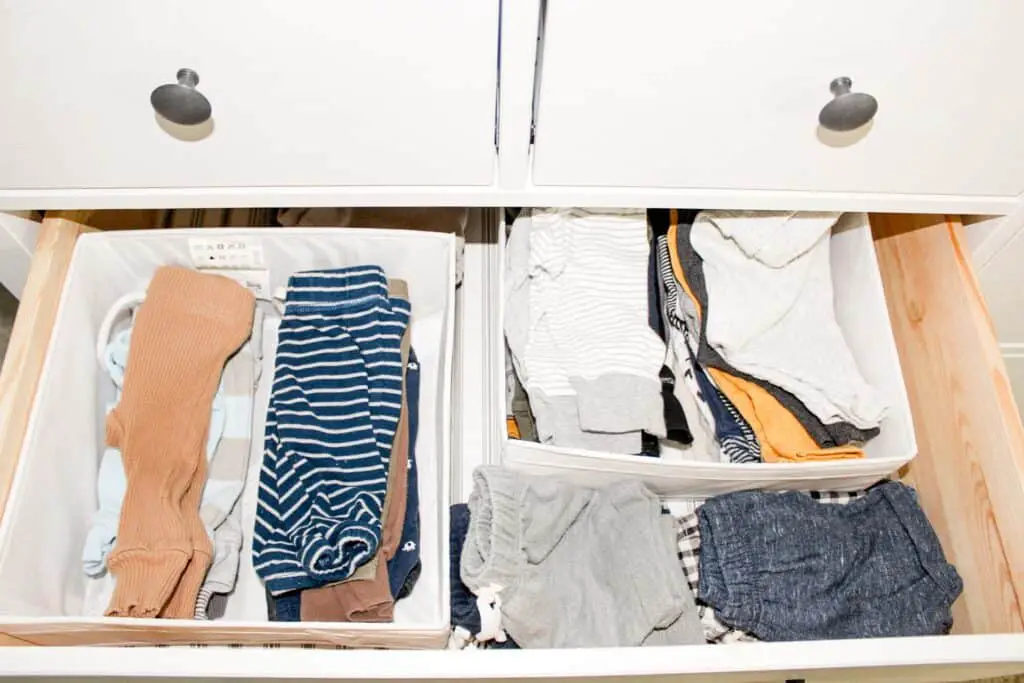 A drawer with drawer organizers that house pants and some shorts for baby alongside the organizers.
