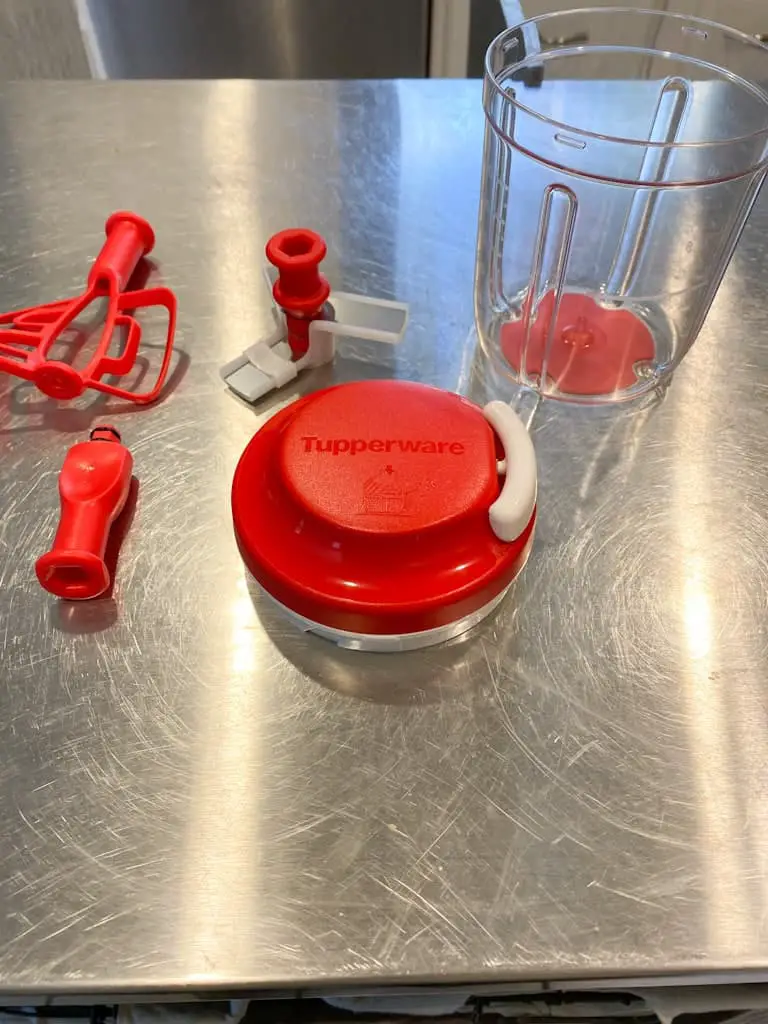 The Supersonic Chopper is another must have Tupperware product. This shows all the pieces that come with it. There is the clear plastic container that holds the food, the lid with the pull string inside, the 2-piece center piece that is either a set of 3 blades or a paddle plus the piece it connects to which helps it spin.