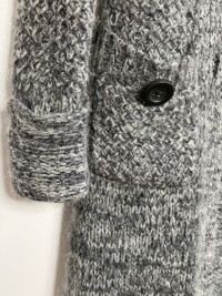 A close up showing the rolled sleeve of the marled gray and white duster cardigan.