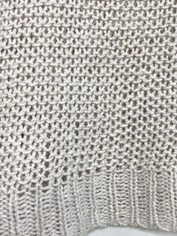 Close up showing the detail of the gray open knit sweater.