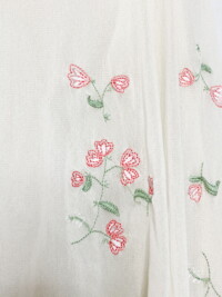 Close up of the pink floral embroidery on the cream sheer button down top.