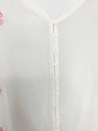 Close up of the buttons on the cream sheer button down top.