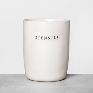 A white ceramic kitchen utensil holder with the word utensils engraved in black. Perfect gift for someone who loves to decorate their kitchen.