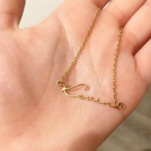A gold necklace with a name written in cursive. A great holiday gift for her.