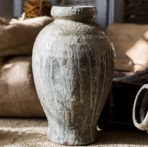 A black vase with coarse texture on it.